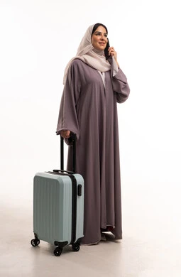 Saudi Woman in Abaya with Suitcase on White Background