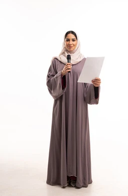 مذيعة سعودية تمسك ميكروفون وورقة في استوديو