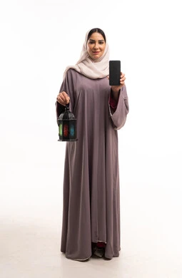 امرأة عربية بالعباءة تحمل هاتف ذكي وفانوس رمضان