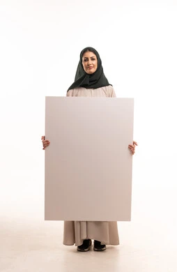 امرأة سعودية تحمل لوحة إعلانية بيضاء فارغة في استوديو