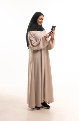 Saudi Woman in Beige Abaya Using Smartphone in Studio