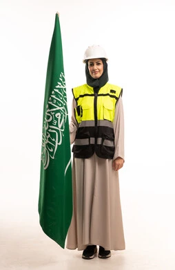 مهندسة سعودية تحمل العلم السعودي بزي العمل والأمان