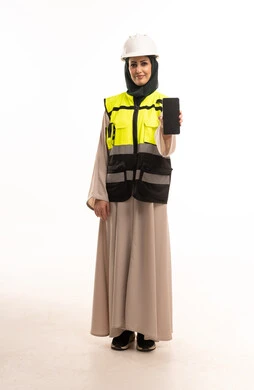مهندسة عربية تمسك هاتفاً ذكياً بملابس السلامة المهنية