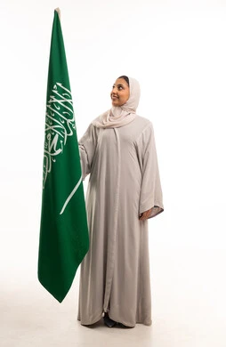 امرأة سعودية تحمل العلم الوطني السعودي بخلفية بيضاء