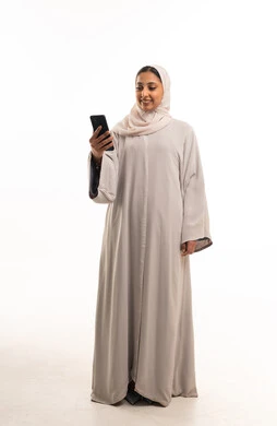 امرأة سعودية بالعباءة تستخدم الهاتف الذكي في الاستوديو