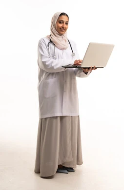 طبيبة سعودية تحمل جهاز لابتوب بخلفية بيضاء