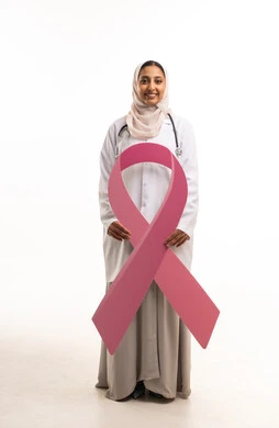 طبيبة سعودية مع شريط التوعية بسرطان الثدي