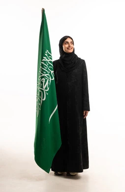 امرأة سعودية بالعباءة تحمل علم المملكة العربية السعودية