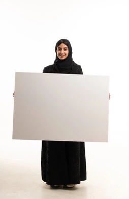 امرأة سعودية بالعباءة تحمل لوحة بيضاء في استوديو