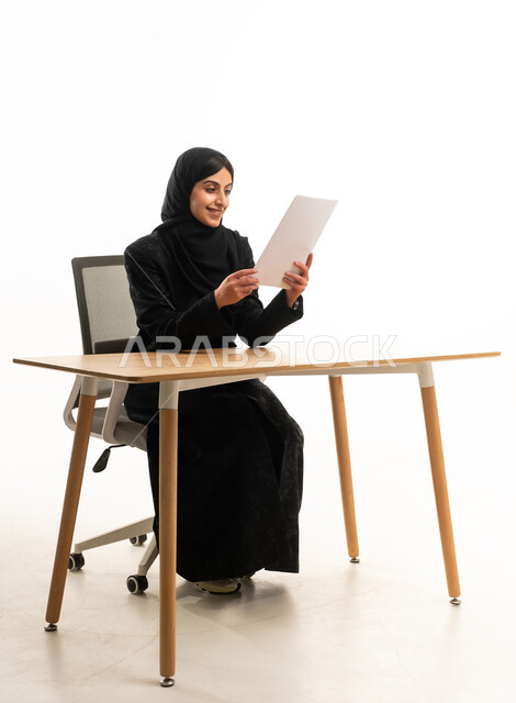 سيدة أعمال سعودية تقرأ وثيقة في مكتب عصري