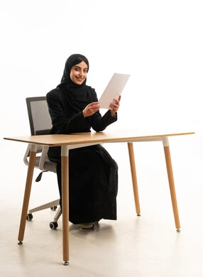 سيدة أعمال سعودية بالعباءة تجلس خلف مكتب عمل