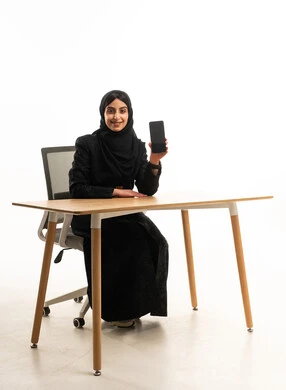 امرأة سعودية تحمل هاتفاً ذكياً في المكتب