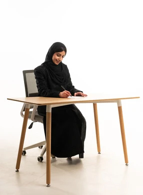 سيدة أعمال إماراتية تكتب على مكتب حديث