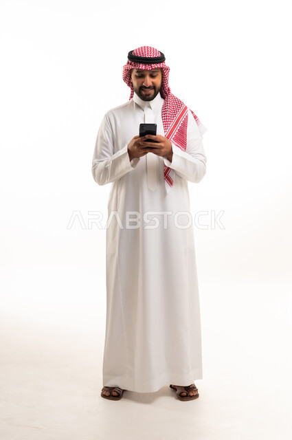 رجل سعودي بالزي التقليدي يستخدم الهاتف الذكي في الاستوديو