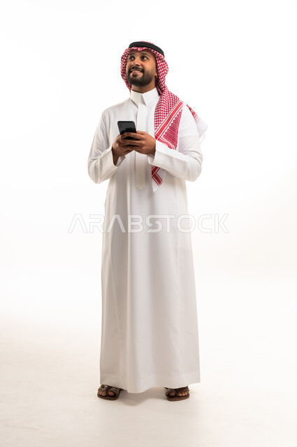رجل سعودي بالزي التقليدي يمسك هاتف ذكي