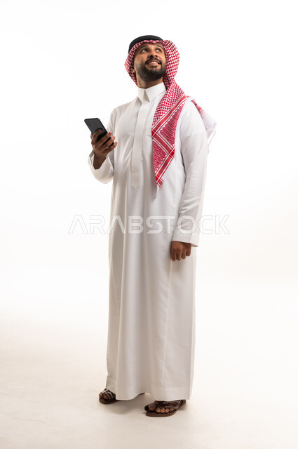 رجل سعودي مع هاتف ذكي في استوديو بخلفية بيضاء