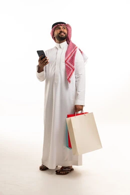 رجل سعودي يحمل حقائب تسوق وهاتف ذكي في الاستوديو