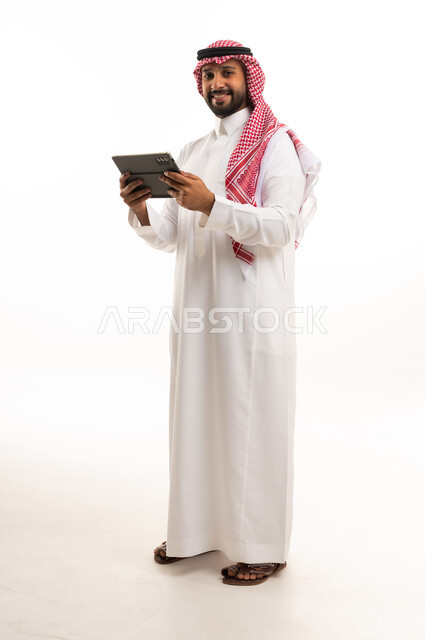 رجل سعودي يحمل جهاز لوحي بخلفية بيضاء