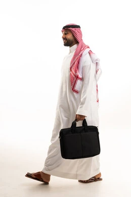 رجل أعمال سعودي بالزي التقليدي يمشي مع حقيبة