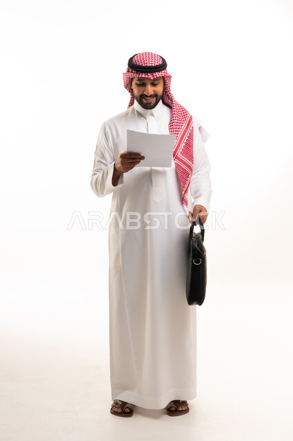 Saudi Businessman in Traditional Thobe Reading Document