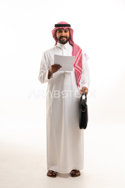 رجل أعمال سعودي يحمل ورقة وحقيبة على خلفية بيضاء