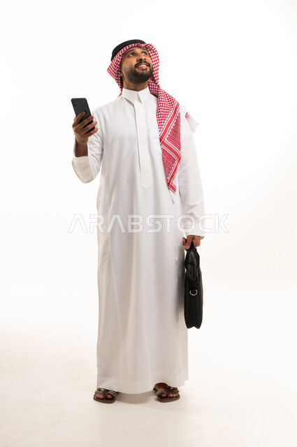 رجل أعمال سعودي مع هاتف ذكي وحقيبة عمل