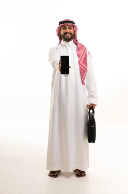 رجل سعودي بالثوب الأبيض يحمل شاشة هاتف ذكي
