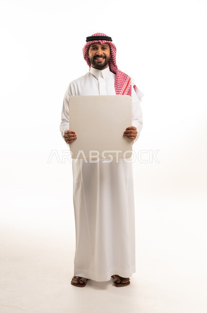 رجل سعودي بالزي التقليدي يحمل لوحة فارغة