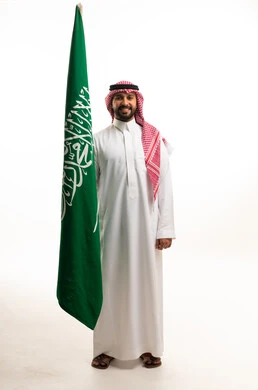 رجل سعودي يحمل علم السعودية بخلفية بيضاء