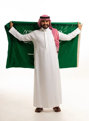رجل سعودي يحمل علم المملكة بالزي التقليدي
