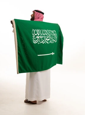 رجل سعودي يحمل علم المملكة العربية السعودية من الخلف
