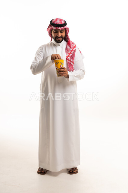 Saudi Man in Traditional Thobe Eating Popcorn