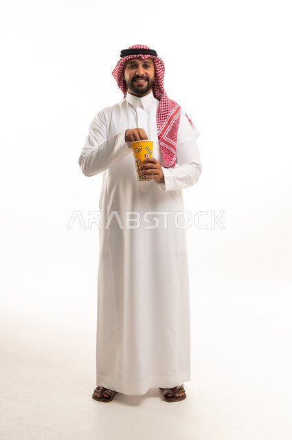 رجل سعودي بالزي التقليدي يتناول الفشار خلفية بيضاء
