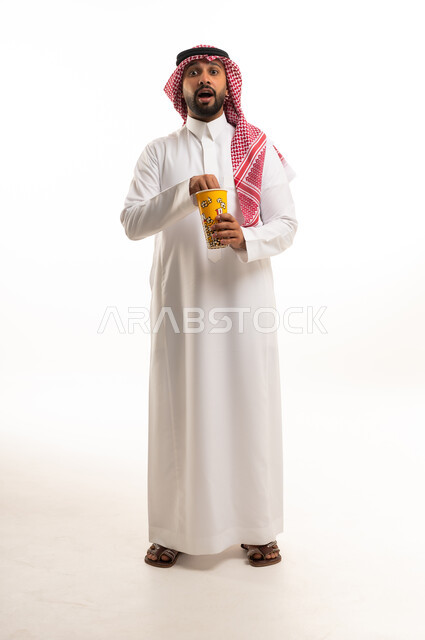 رجل سعودي بالثوب التقليدي يحمل الفشار بدهشة