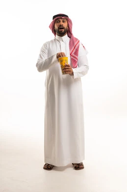 رجل سعودي بالثوب التقليدي يحمل الفشار بدهشة