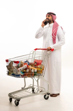 رجل سعودي مع عربة تسوق وهاتف ذكي خلفية بيضاء