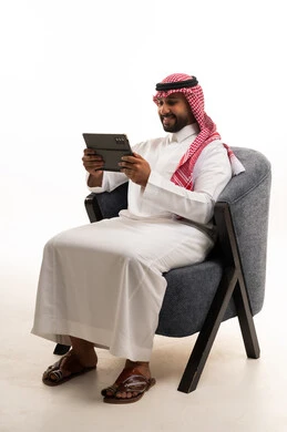 رجل سعودي بالثوب التقليدي يستخدم جهاز لوحي