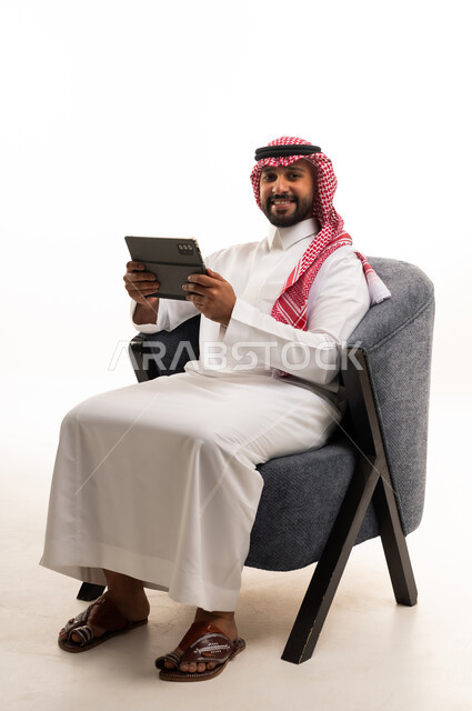 رجل سعودي مع جهاز لوحي بالثوب التقليدي والشماغ