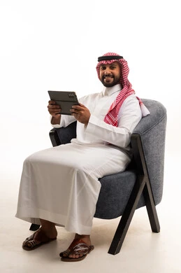 رجل سعودي مع جهاز لوحي بالثوب التقليدي والشماغ
