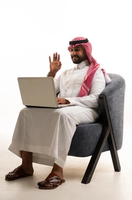 A Saudi man using a laptop in traditional attire.