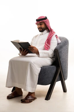 رجل سعودي بالزي التقليدي يقرأ كتاباً في الاستوديو