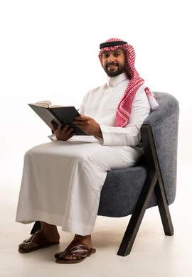رجل سعودي بالزي التقليدي يقرأ كتاباً في الاستوديو