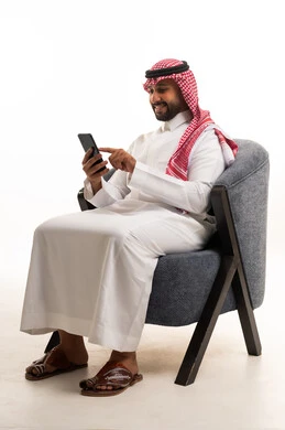 رجل سعودي بالثوب التقليدي يستخدم الهاتف الذكي