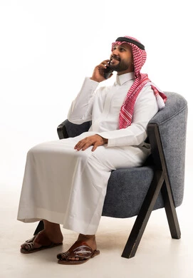 رجل سعودي بالثوب التقليدي يستخدم الهاتف الذكي