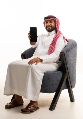 رجل سعودي بالثوب التقليدي يستخدم الهاتف الذكي