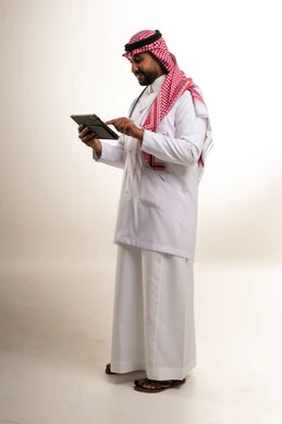 طبيب سعودي يرتدي المعطف الطبي ويستخدم جهاز تابلت رقمي