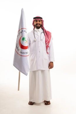 طبيب سعودي يحمل علم الهلال الأحمر بخلفية بيضاء