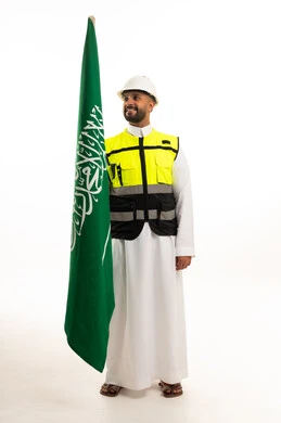 رجل سعودي يحمل العلم الوطني بالثوب التقليدي وسترة الحماية