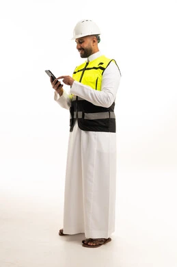 مهندس سعودي يرتدي سترة السلامة ويستخدم الجوال