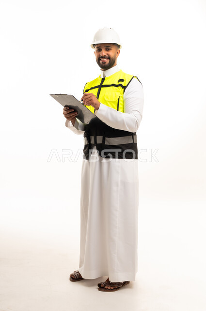 مهندس سعودي يرتدي سترة السلامة ويمسك لوحة ملاحظات